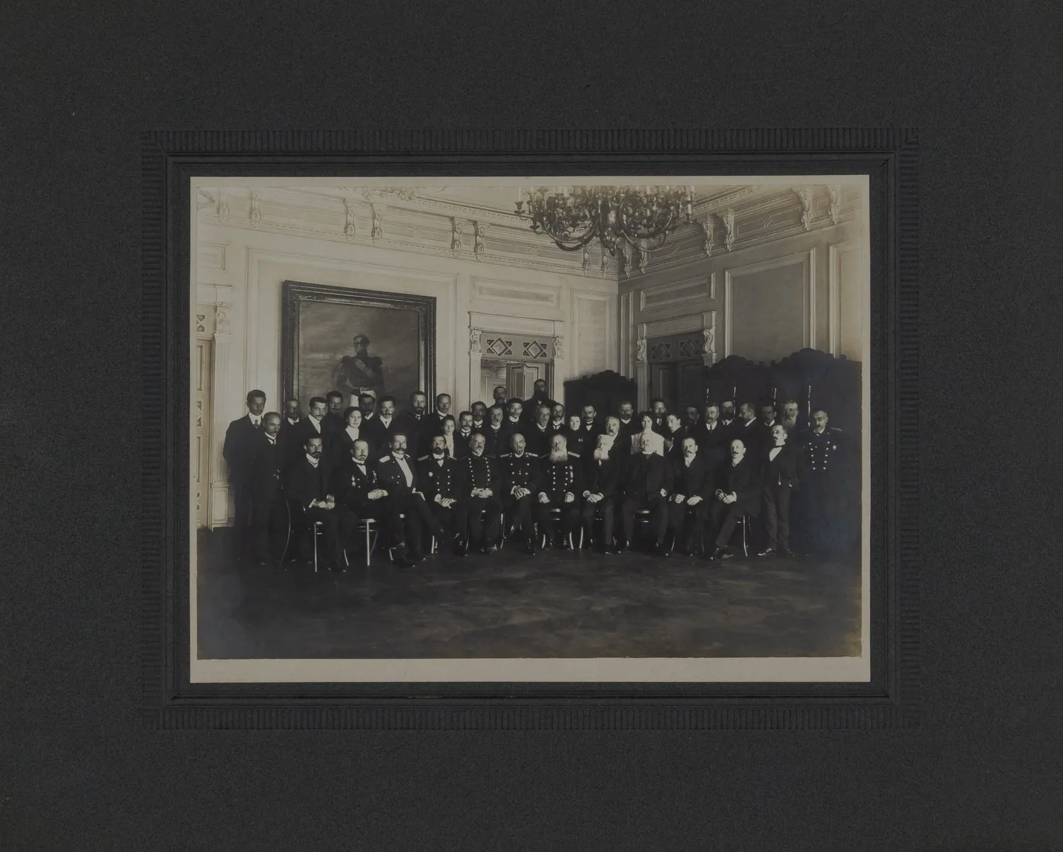 Групповая постановочная фотография на фоне портрета Николая I работы И.В. Гудовского. Нач. XX века. — фото 1
